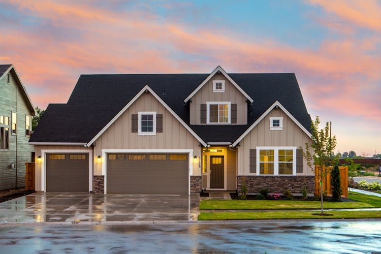 Lawn sprinkler system watering green grass in front of a modern home